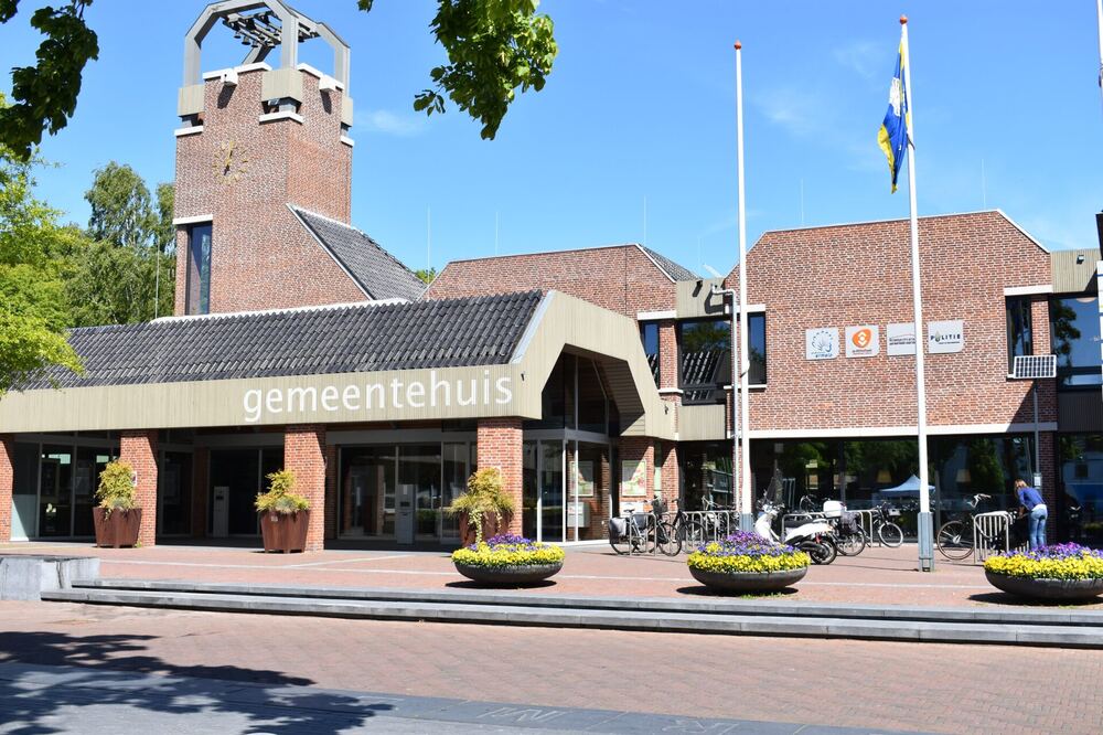 Gemeentehuis van Ermelo met klokkentoren, vlaggen en fietsen op het plein